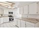 Bright kitchen with white cabinets, tile countertops, and modern stainless steel appliances at 6717 E Saddleback Cir, Mesa, AZ 85215