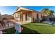 View of the home's backyard with green grass, block wall, covered patio, and beige exterior at 815 E Centre Ave, Buckeye, AZ 85326