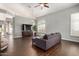 Open floorplan living room boasts dark wood-look flooring and a stylish gray sofa and television at 901 N Woodburne Dr, Chandler, AZ 85224