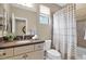 Well-lit bathroom features a vanity with a dark countertop, a toilet, and a shower/tub combo with a striped shower curtain at 908 E Cereus Pass, Queen Creek, AZ 85140