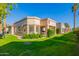 Manicured backyard featuring lush green grass, mature trees, and a covered patio area, perfect for relaxation at 9329 W Topeka Dr, Peoria, AZ 85382