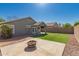 Backyard featuring artificial turf, a fire pit, rock landscaping, and a covered patio at 10704 E Plata Ave, Mesa, AZ 85212