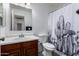 Bathroom with wood vanity, toilet and tub/shower featuring a black and white cactus curtain at 10704 E Plata Ave, Mesa, AZ 85212