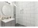 Well-lit bathroom features a walk-in shower, gray vanity, round mirror, and modern tiles at 12201 N 66Th St, Scottsdale, AZ 85254