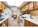 Cozy kitchen featuring wood cabinetry, white appliances, and a view of the adjacent living space at 1402 E Guadalupe Rd # 145, Tempe, AZ 85283