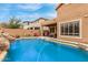 Backyard view featuring a refreshing pool with a rock waterfall, alongside a covered patio for outdoor entertaining at 16830 S Coleman St, Phoenix, AZ 85045