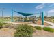 A community playground shaded by a large sail, featuring various play structures at 17055 W El Caminito Dr, Waddell, AZ 85355