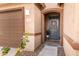 Close-up of the front door with a charming wreath, potted plant, and brown trim, with a view of the garage at 1743 W Flintlock Dr, San Tan Valley, AZ 85144