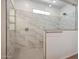 Modern bathroom shower with marble tiled walls and a frameless glass door at 18432 W Mohave St, Goodyear, AZ 85338