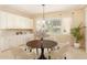 Dining area with a round wooden table, modern chandelier, and three large windows at 19318 E Walnut Rd, Queen Creek, AZ 85142