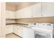 Clean laundry room with front-load washer/dryer and ample cabinet space at 19318 E Walnut Rd, Queen Creek, AZ 85142