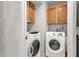 Functional laundry room with upper cabinets and modern GE and Samsung washer and dryer at 1975 E Sunburst Ln, Tempe, AZ 85284