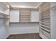 This walk-in closet features custom white shelving and storage options, with carpet flooring at 3023 W Quail Ave, Phoenix, AZ 85027