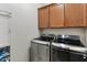 Efficient laundry room with side-by-side stainless steel washer and dryer, and convenient overhead cabinets at 31061 N 136Th Ln, Peoria, AZ 85383