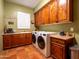 Functional laundry room with wooden cabinetry, tile floors, and modern appliances at 31816 N 19Th Ave, Phoenix, AZ 85085