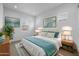 Bright main bedroom with natural light, a large bed with a turquoise throw, and decorative wall art at 34283 N Sandpiper Trl, Queen Creek, AZ 85144