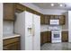 Bright kitchen with white appliances, white countertops, and dark wood cabinets at 3864 W Fairway Dr, Eloy, AZ 85131