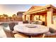 Outdoor dining area with stone table next to a private pool and covered patio at 42829 W Oakland Dr, Maricopa, AZ 85138