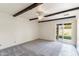 Bright bedroom with wood beam accents, ceiling fan, and a sliding glass door to backyard at 4312 W Paradise Dr, Glendale, AZ 85304