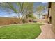 Lush backyard with artificial grass, brick patio and walkway, hot tub, and mature trees at 44025 N 44Th Ln, New River, AZ 85087