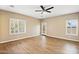 Bright living room with wood floors, ceiling fan, and large windows with plantation shutters at 44025 N 44Th Ln, New River, AZ 85087