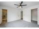 A well-lit bedroom showcasing gray carpet, ceiling fan, and doors to closet and bathroom at 4814 E Pearce Rd, Phoenix, AZ 85044