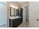 Bathroom with dual sink vanity, a mirror, lighting, cabinet, and an open closet door at 551 E Citrus Hollow Way, Queen Creek, AZ 85140