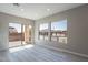 Bright living room with wood-look floors, neutral walls, and sliding glass door to outside area at 551 E Citrus Hollow Way, Queen Creek, AZ 85140