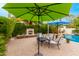 Cozy patio area features a fireplace, comfortable seating, and shade from a green umbrella at 5948 W Leiber Pl, Glendale, AZ 85310