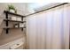 Well-organized bathroom with open wood shelves, toilet, and a patterned shower curtain at 853 E Ross Ave, Phoenix, AZ 85024