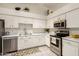 Well-lit kitchen featuring white cabinets, stainless steel appliances, and ample counter space for food preparation at 870 S Palm Ln # 55, Chandler, AZ 85225