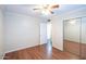 Bedroom features wood laminate flooring, a mirrored closet, neutral walls, and a ceiling fan at 909 W San Mateo Ct, Gilbert, AZ 85233