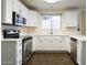 Well-lit kitchen features stainless steel appliances, white cabinets, countertops, and sleek hardware at 909 W San Mateo Ct, Gilbert, AZ 85233