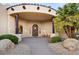 A beautiful covered entryway featuring a custom wood door, desert landscaping, and stone accents at 9160 E Wethersfield Rd, Scottsdale, AZ 85260