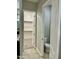 Hallway view of bathroom and walk-in closet in home, showcasing neutral color palette and tile flooring at 10508 W Odeum Ln, Tolleson, AZ 85353