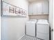 Well-lit laundry room with upper cabinets, modern washer and dryer and decorative floor tiles at 14598 W Wood Dr, Surprise, AZ 85379