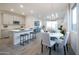 Open-concept living space with modern light fixture, grey wood floors, and an island with seating at 14598 W Wood Dr, Surprise, AZ 85379