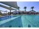 Community pool features in-water seating, umbrellas, and shade sails, surrounded by palm trees and well-maintained landscaping at 14598 W Wood Dr, Surprise, AZ 85379