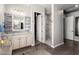 Bathroom featuring dual sinks with white cabinetry, a large mirror, and open access to the walk-in shower at 15997 W Vernon Ave, Goodyear, AZ 85395