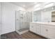 A bright bathroom featuring a glass enclosed shower, double sinks, and hardwood floors at 18447 W Mohave St, Goodyear, AZ 85338