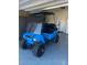 Bright blue golf cart with black seats and accents parked inside garage with epoxy flooring at 18619 W Smoketree Dr, Surprise, AZ 85387