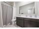 Neutral bathroom featuring a shower with a gray curtain, toilet, and a vanity with a large mirror at 18619 W Smoketree Dr, Surprise, AZ 85387