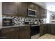 Modern kitchen with stainless steel appliances, dark wood cabinets, and a stylish backsplash at 1973 N Lewis Pl, Casa Grande, AZ 85122