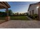 Backyard boasts travertine patios, grassy lawn, landscaped beds and string lights for evening enjoyment at 19777 E Ivy Ln, Queen Creek, AZ 85142