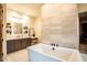 Bright bathroom features a soaking tub, tile accent wall, dark cabinets and light countertops at 19777 E Ivy Ln, Queen Creek, AZ 85142