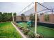 Private backyard batting cage nestled among mature landscaping and lush green lawn, perfect for practice at 19777 E Ivy Ln, Queen Creek, AZ 85142