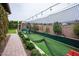 Exterior shot of a private batting cage with synthetic turf and safety netting, surrounded by manicured landscaping at 19777 E Ivy Ln, Queen Creek, AZ 85142