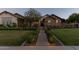 Traditional brick facade is enhanced by a manicured lawn, lush landscaping, and a quaint walkway at 19777 E Ivy Ln, Queen Creek, AZ 85142