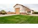Exterior view of garage and front yard with green grass and desert landscaping at 19777 E Ivy Ln, Queen Creek, AZ 85142