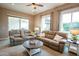 Open living room features neutral walls, large windows, ceiling fan, and multiple seating options at 19777 E Ivy Ln, Queen Creek, AZ 85142